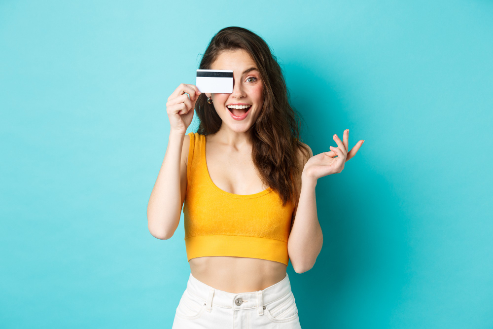 excited beautiful woman summer cropped top look amazed camera shopping with credit card standing blue background